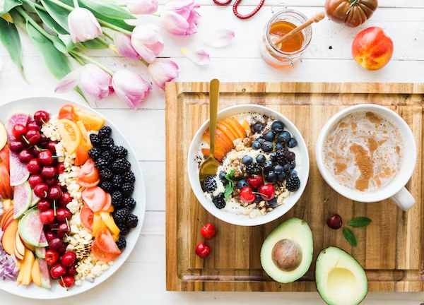 an oatmeal bowl, smoothie bowl, avocado, and a dish filled with many fruits like cherries, blackberries, Strawberries, peaches, apples, guavas, and nuts