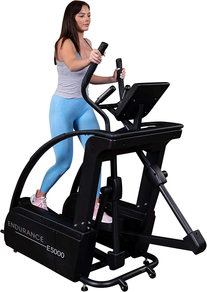 a woman wearing blue trousers while working on the elliptical machine
